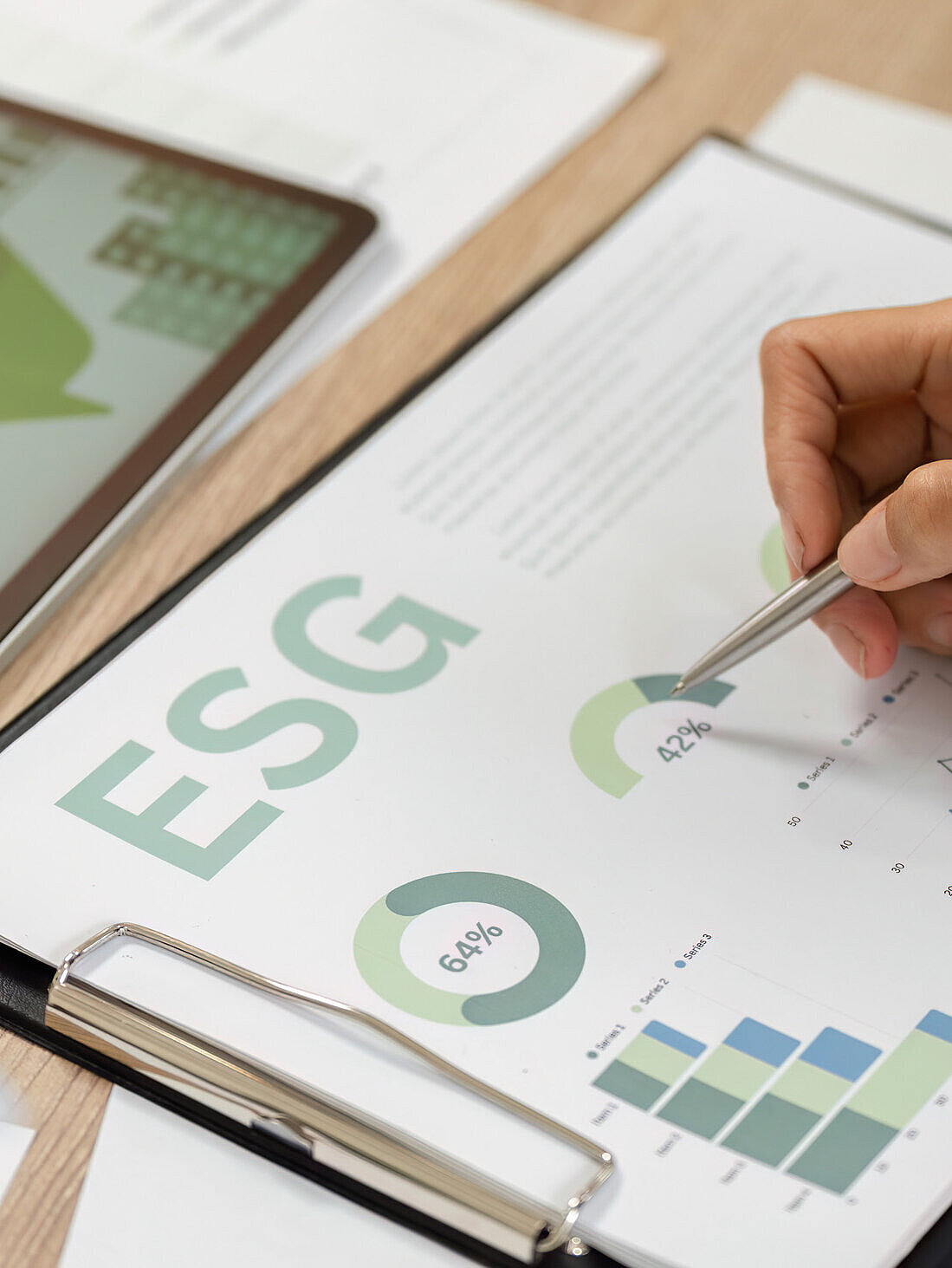 Hand mit einem Stift, die ein Datenblatt zum Thema "ESG" bearbeitet.
