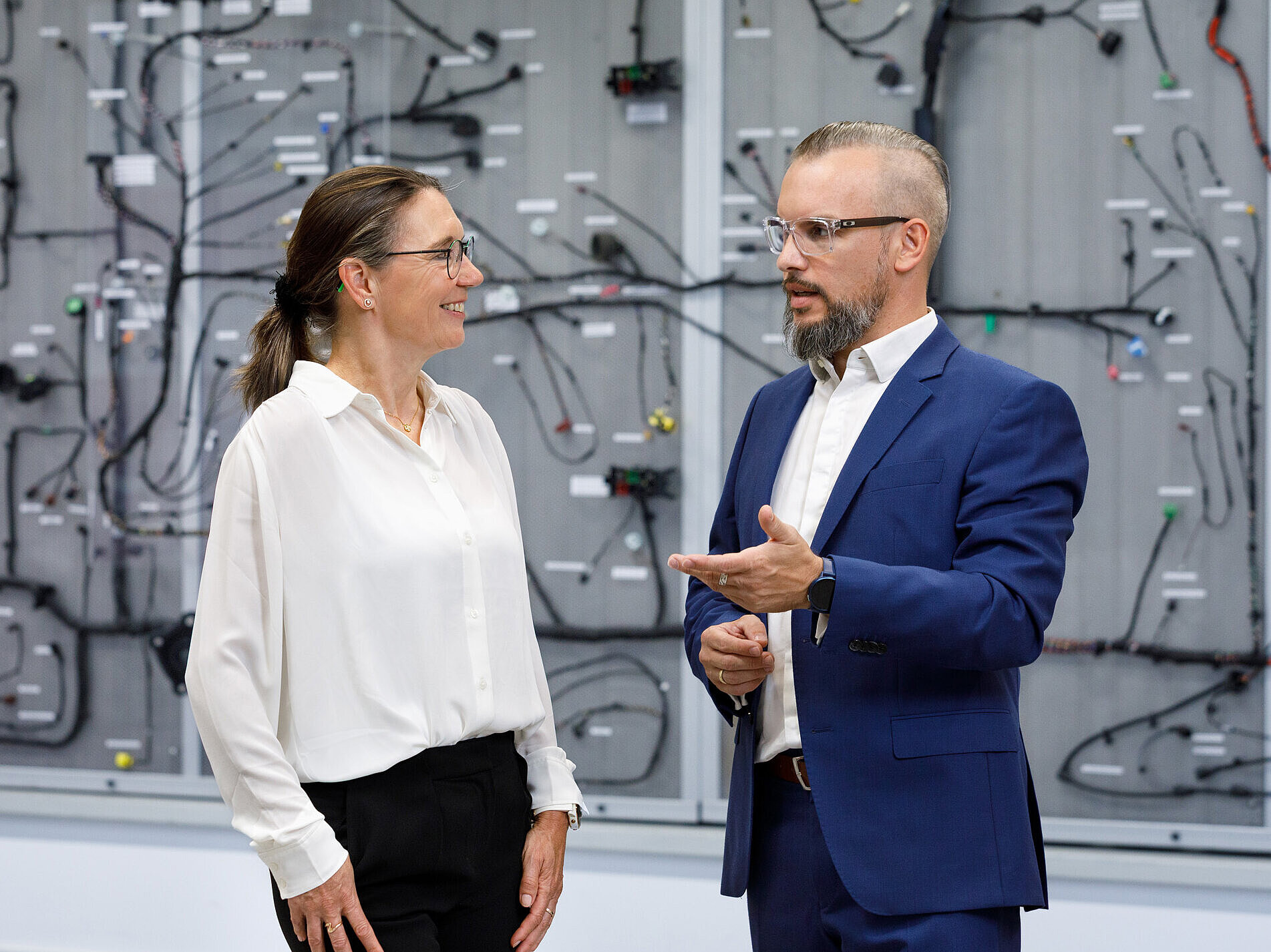 Gesprächssituation zwischen zwei Personen vor einem Bordnetz.